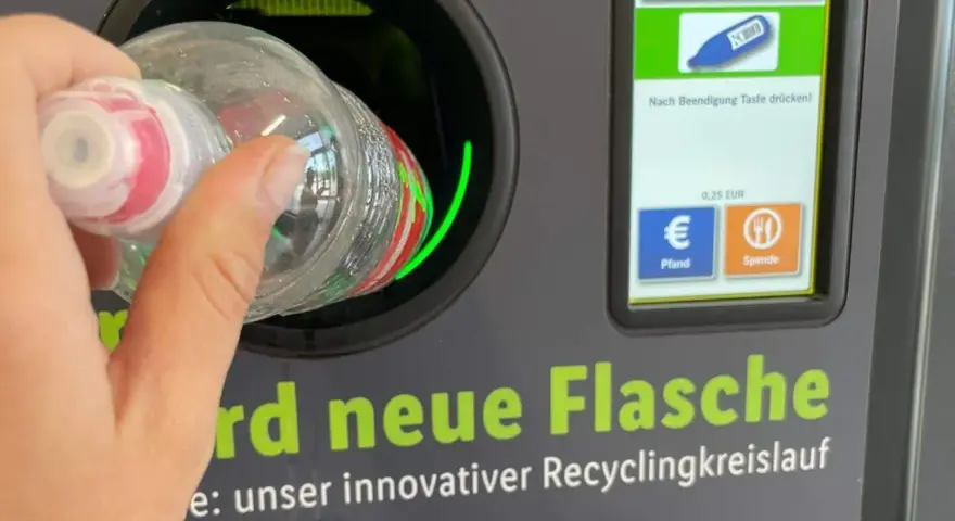 Ręka wrzuca butelkę do automatu. Niemiecki system kaucyjny działa sprawnie, zwracając 0,25 EUR za każdy zwrot.