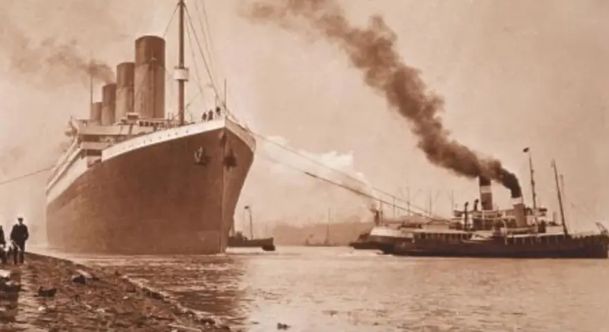 Ogromny statek, prawdopodobnie **Titanic**, wypływa z portu, holowany przez mniejsze jednostki. Dym unosi się z kominów.