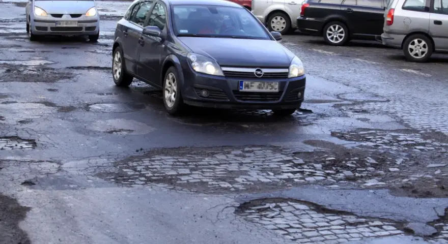 Samochody jadą po dziurawej drodze. Czy warto wykupić ubezpieczenie Europa Ubezpieczenia opinie?