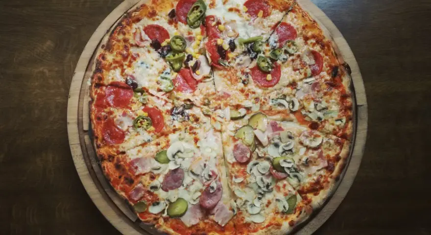 Pizza 32 cm z różnymi dodatkami: salami, kukurydza, jalapeno, pieczarki, ogórek, szynka.