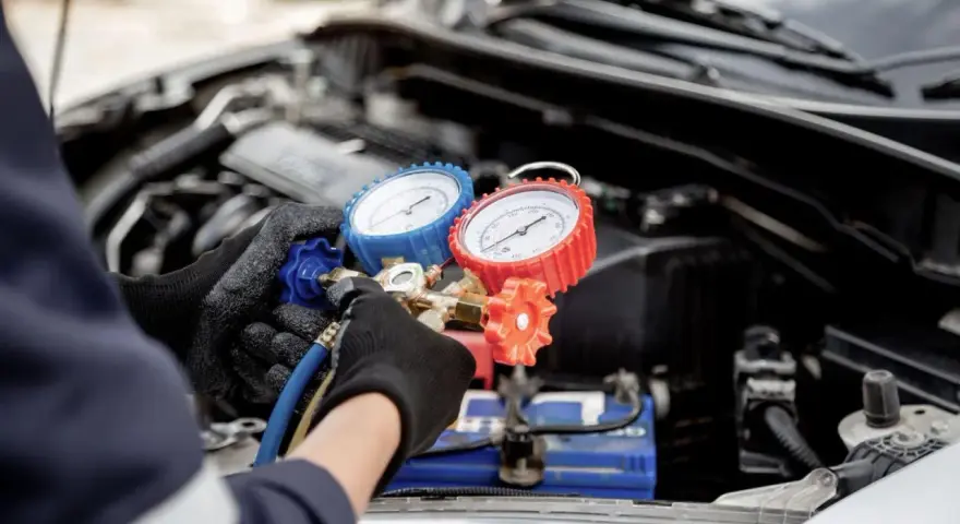 Mechanic checks car AC pressure with gauges. This helps determine how much to fix AC in car.