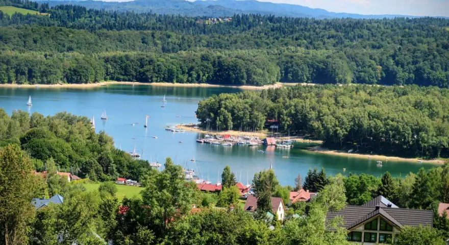 Malownicze Bieszczady z dziećmi: jezioro, żaglówki, las i domki letniskowe. Idealne miejsce na wakacje.