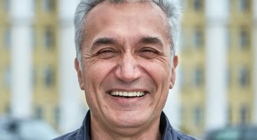 Uśmiechnięty mężczyzna z siwymi włosami, który wygląda jak typowy boomer. Co to znaczy? To ktoś z pokolenia wyżu demograficznego, często kojarzony z pewnymi wartościami i stylem życia.
