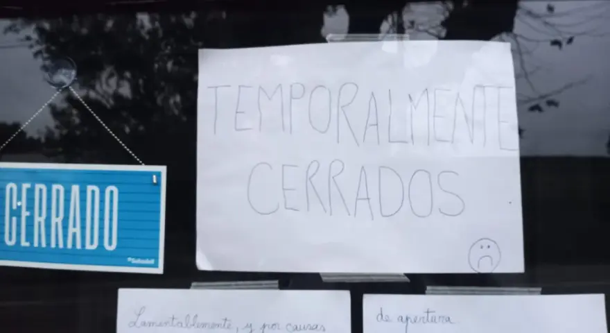 Cartel de "CERRADO" y otro escrito "TEMPORALMENTE CERRADOS" en la ventana de un bar restaurante.