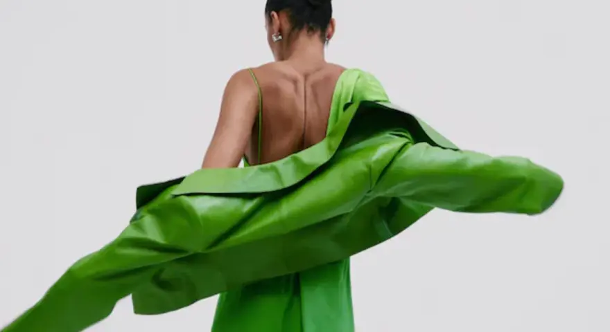 Mujer con un vestido verde brillante y una chaqueta verde vibrante. Un look audaz para combinar vestido verde con chaqueta.