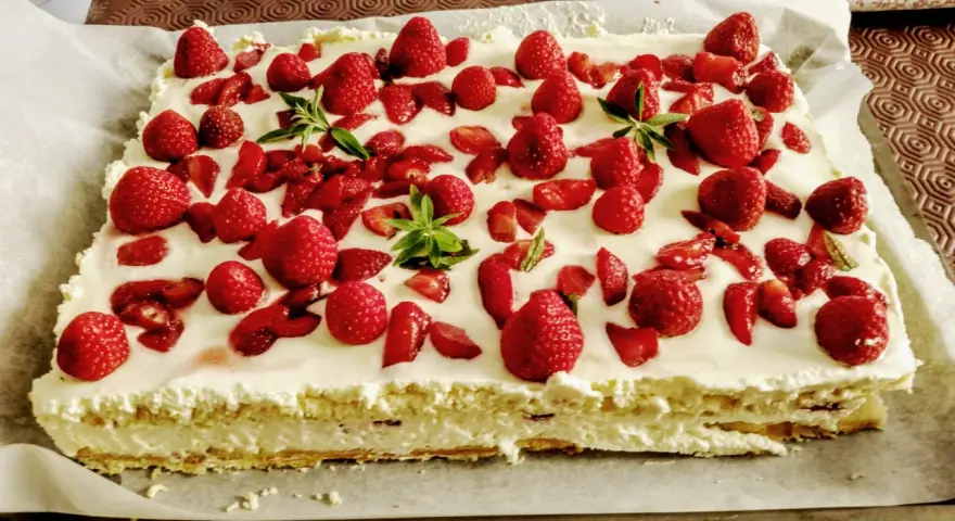 Un délicieux entremet fraise, garni de fruits rouges frais et de feuilles de menthe, sur une base crémeuse.