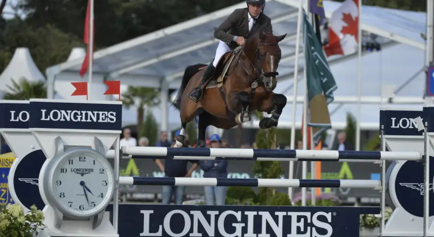 Le cavalier Cooper van de Heffinck et son cheval sautent un obstacle lors d'une compétition équestre.