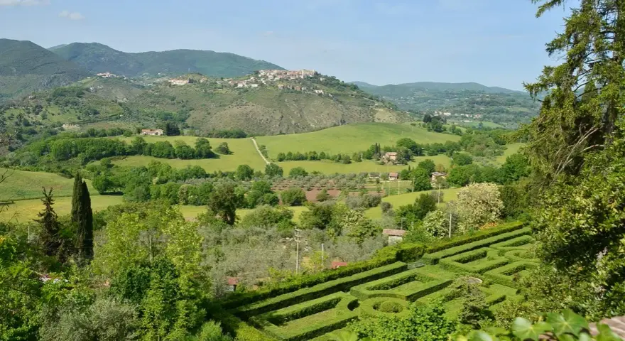 Un labirinto verdeggiante si apre su dolci colline e borghi arroccati nei Monti Sabini, un paesaggio idilliaco sotto un cielo azzurro.