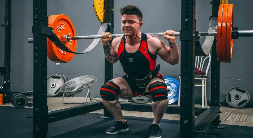 En person utför squats med vikt i ett gym.