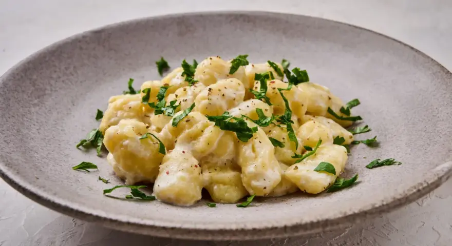 Pyszne gnocchi z kremowym sosem, posypane świeżą natką pietruszki. Idealne danie dla każdego miłośnika włoskiej kuchni.