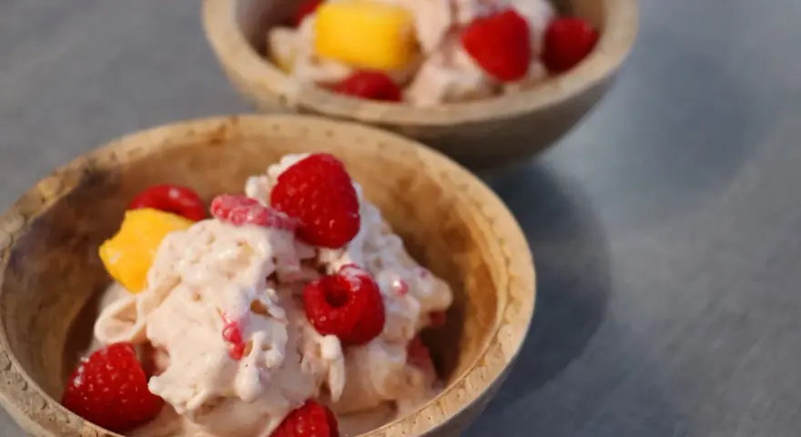 Två skålar med krämig proteinglass, toppad med hallon och mangobitar. Ett perfekt recept för en hälsosam dessert.