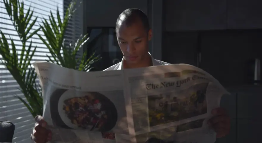 Mężczyzna czyta "The New York Times", zastanawiając się, czy urlop przechodzi do nowego pracodawcy.