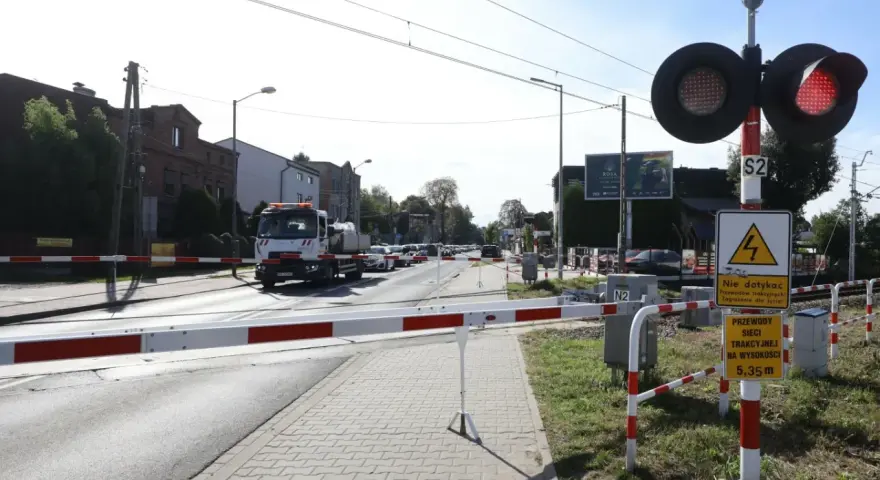 Przejazd kolejowy z zaporami i czerwonymi światłami. Samochód ciężarowy czeka na przejazd.