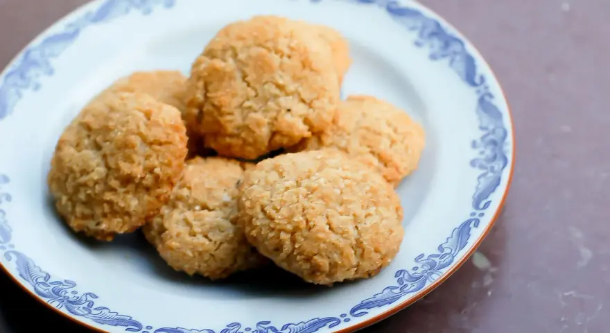 En tallrik med gyllene, glutenfria kakor med kokosflingor. Perfekt för fikat!