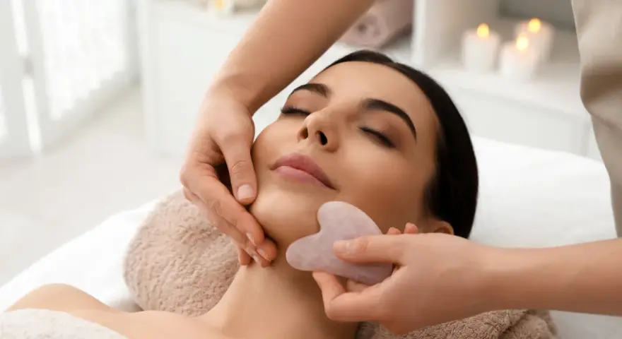 Relaksacyjny masaż twarzy kamieniem gua sha. Delikatne ruchy kamienia poprawiają krążenie i odmładzają skórę.