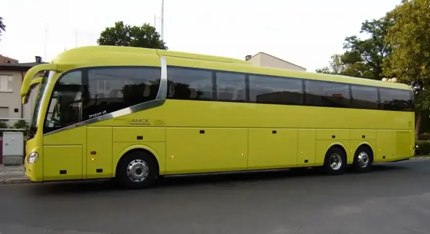 Żółty autokar firmy ANICK stoi na ulicy. Trudno określić, ile miejsc ma autokar, ale wygląda na bardzo pojemny.