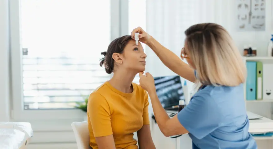 Medico applica cortisone collirio a una giovane paziente in ambulatorio.