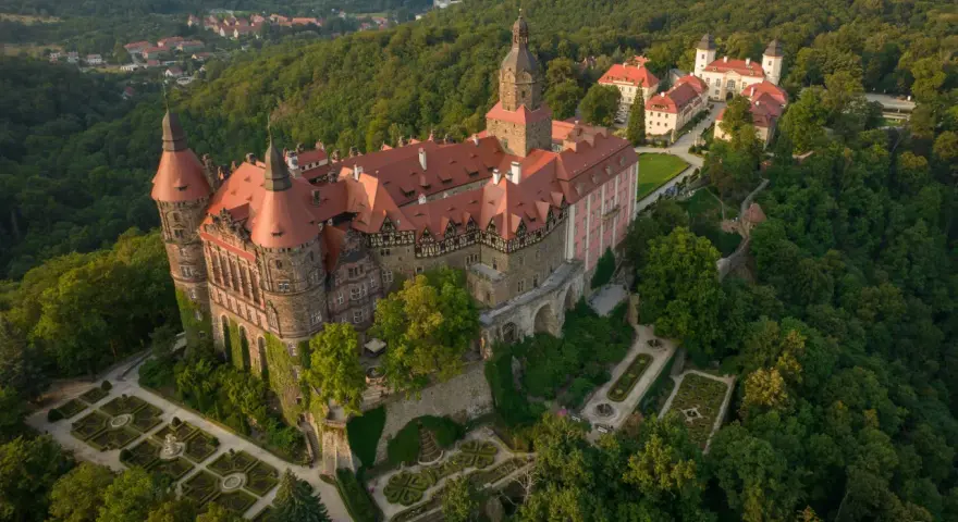 Zamek Książ otoczony zielenią, z pięknymi ogrodami i widokiem na okoliczne góry. To wspaniałe miejsce, by odkrywać atrakcje Gór Sowich.