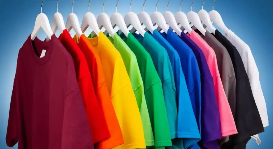 Une rangée de t-shirts colorés sur des cintres blancs, un arc-en-ciel de couleurs pour raviver les couleurs du linge.