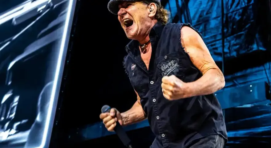 Brian Johnson z AC/DC w Polsce, w szczytowej formie, śpiewa z mikrofonem w dłoni.