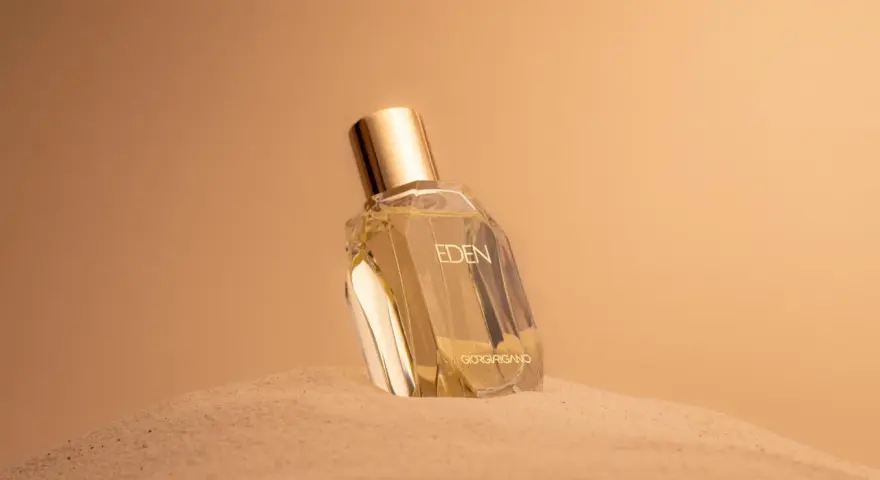 Flacone di profumo "Eden" su sabbia dorata. Un body mist cos'è? Una fragranza leggera per rinfrescarsi.