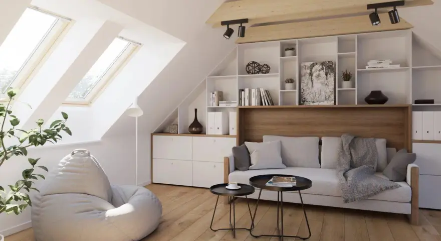 Accogliente salotto in mansarda con divano, pouf, libreria e lucernari che inondano lo spazio di luce.