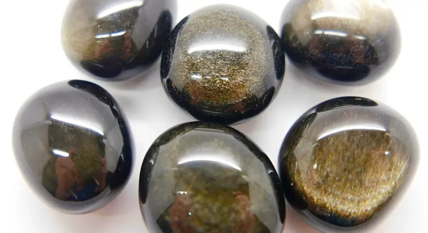 Sei pietre levigate di ossidiana dorata, con riflessi scintillanti che ne rivelano le proprietà uniche.