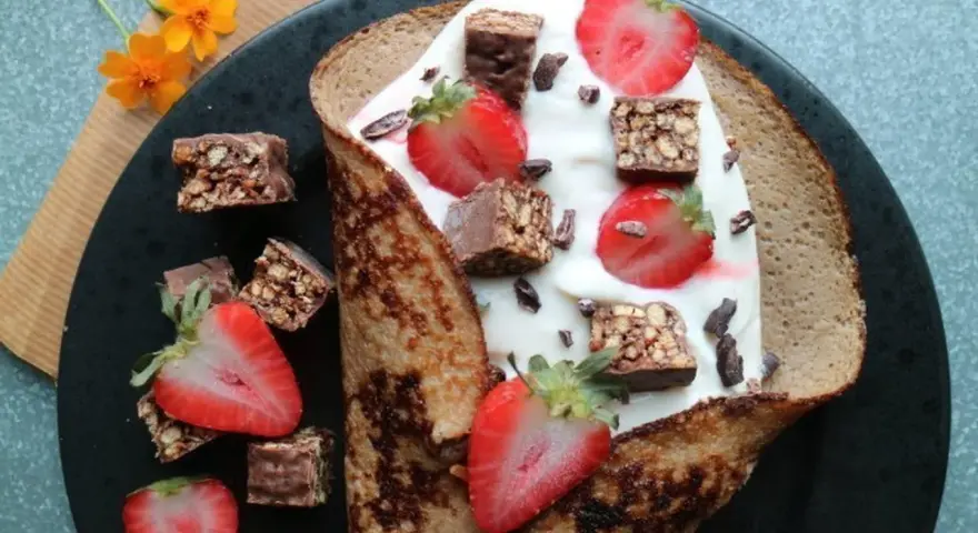 En vikad pannkaka fylld med yoghurt, jordgubbar och chokladbitar. En härlig frukost med nyttiga pannkakor som bas.