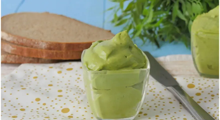 Deliziosa maionese di avocado in una ciotola di vetro, pronta per essere spalmata su fette di pane integrale.
