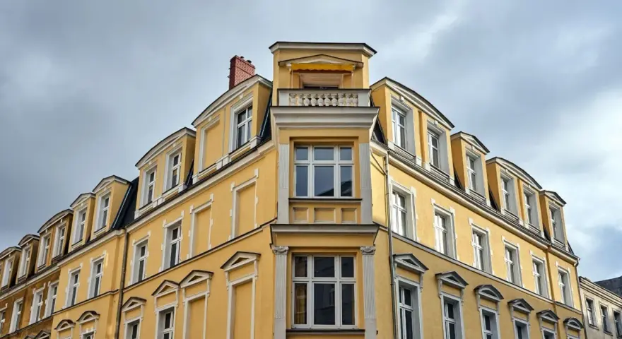 Żółta kamienica z zabytkowymi detalami, gdzie właśnie trwa wymiana okien w budynku wpisanym do gminnej ewidencji zabytków.