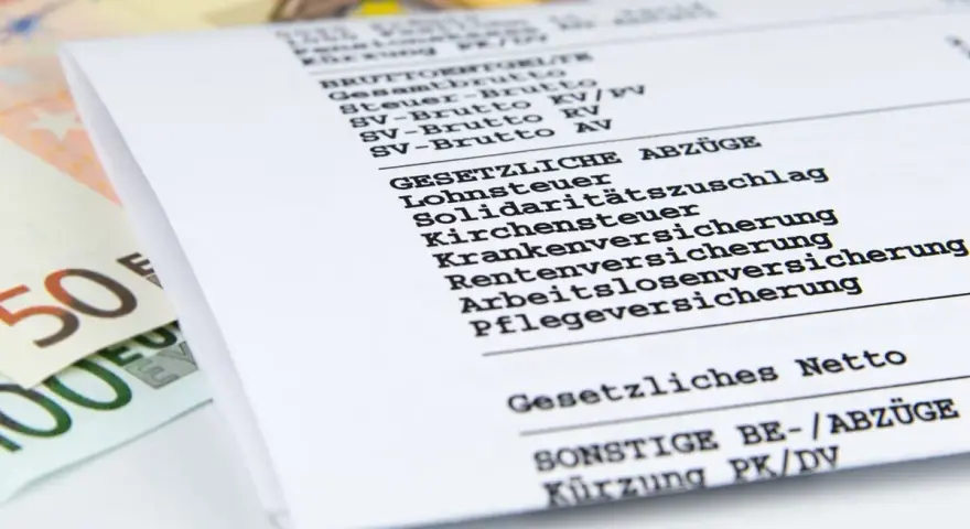 Ausschnitt einer Gehaltsabrechnung mit Posten wie Lohnsteuer, Kirchensteuer und Sozialabgaben. Daneben liegen Euro-Scheine.