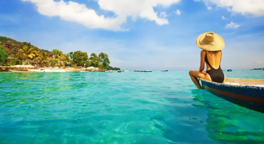 Kobieta w kapeluszu siedzi na łodzi, podziwiając turkusowe morze i tropikalne plaże na Bali.