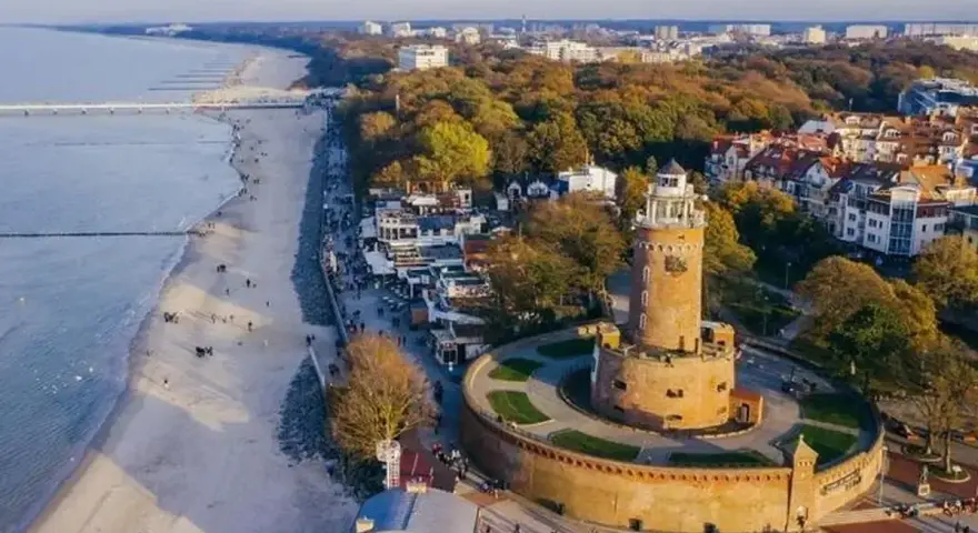 Widok z lotu ptaka na latarnię morską w Darłowie, plażę i nadmorskie miasteczko.