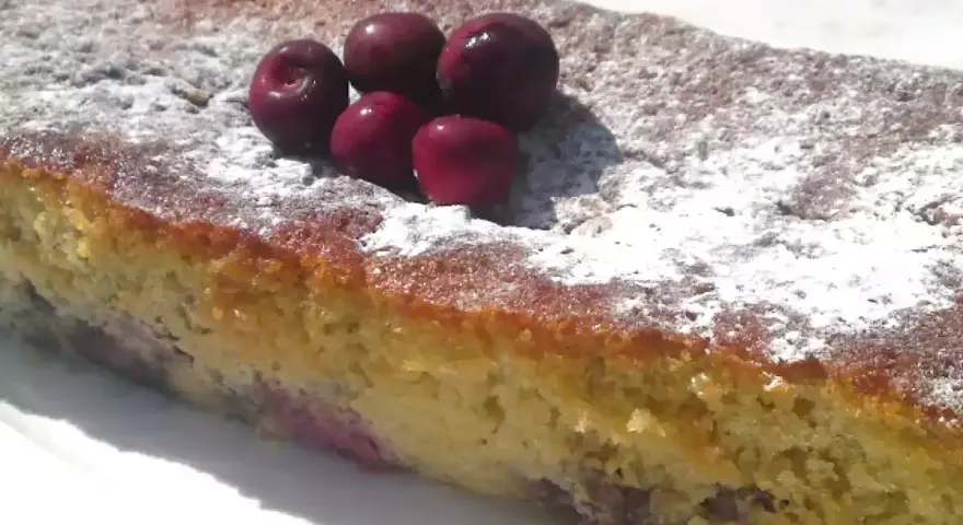 Bizcocho de cerezas casero, espolvoreado con azúcar glas y decorado con cerezas frescas.