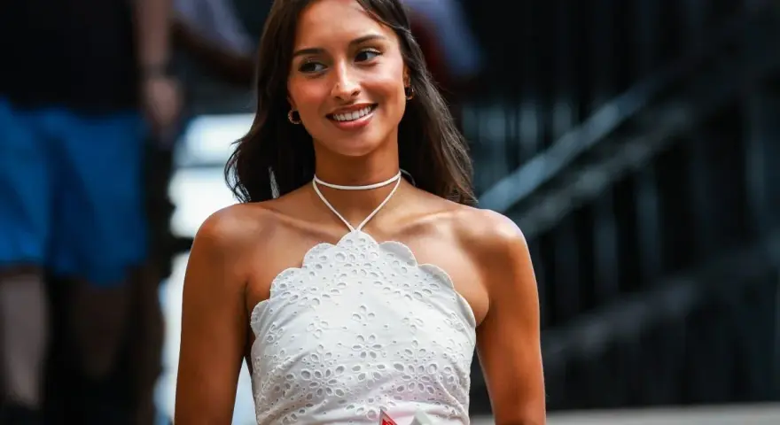 La presunta **Charles Leclerc fidanzata**, Charlotte Siné, sorride con un top bianco ricamato.