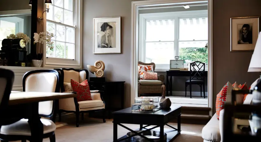Elegante salón con paredes color topo oscuro, muebles clásicos y obras de arte.