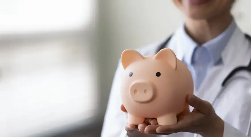 Lekarz rezydent trzyma skarbonkę, zastanawiając się, ile zarabia.