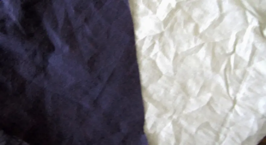 Dwa kawałki materiału, jeden granatowy, drugi biały, przypominają, że **cotton co to** za materiał – miękki i naturalny.