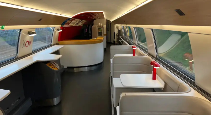 Interior of a TGV train carriage, ready for a journey from Amsterdam to Bordeaux. Booth seating and a bar area await passengers.