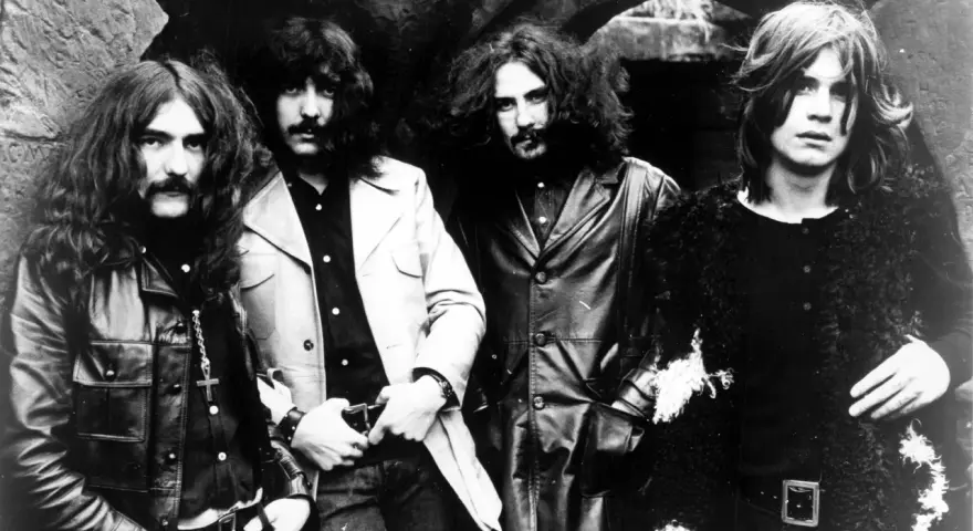 Czterech członków zespołu Black Sabbath, ikony heavy metalu, pozuje do zdjęcia. Ich mroczny styl zapowiadał przełomowe black sabbath albumy.