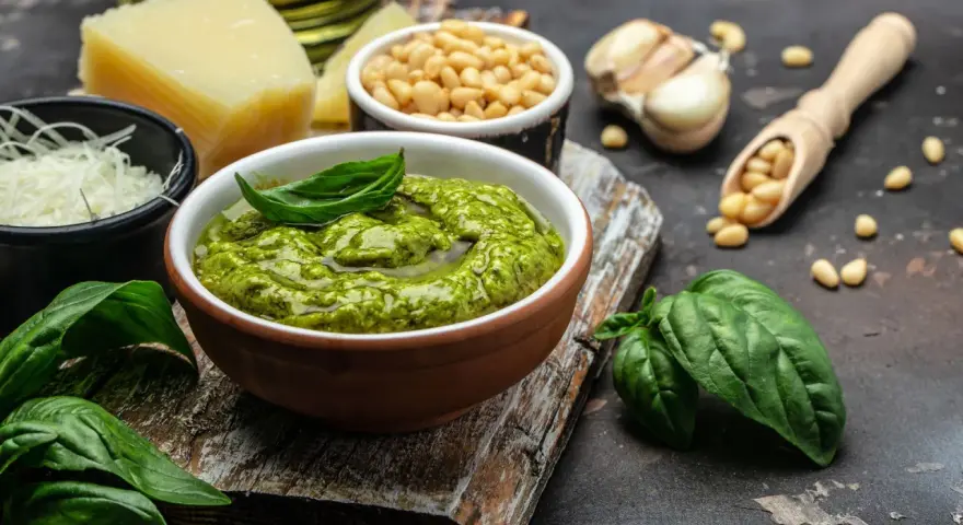 Un tazón de pesto genovés fresco con albahaca, piñones, ajo, queso parmesano y aceite de oliva.