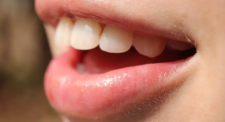 Uśmiech z białymi zębami, usta lekko rozchylone, jakby właśnie użyto nić dentystyczną do ich oczyszczenia.