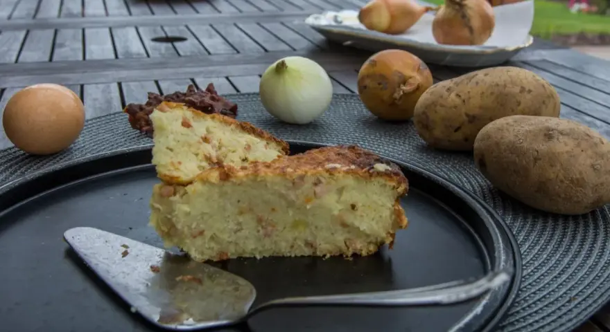 Babka ziemniaczana przepis babci: pyszne ciasto ziemniaczane z boczkiem, jajkiem i cebulą, składniki na stole.
