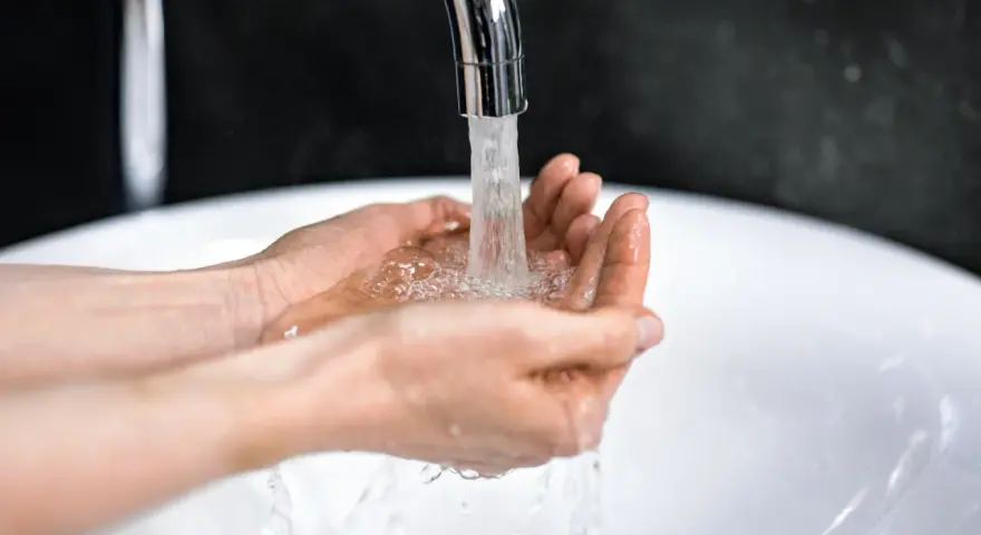 Dłonie łapią strumień wody z kranu. Zastanawiasz się, ile kosztuje kubik wody?