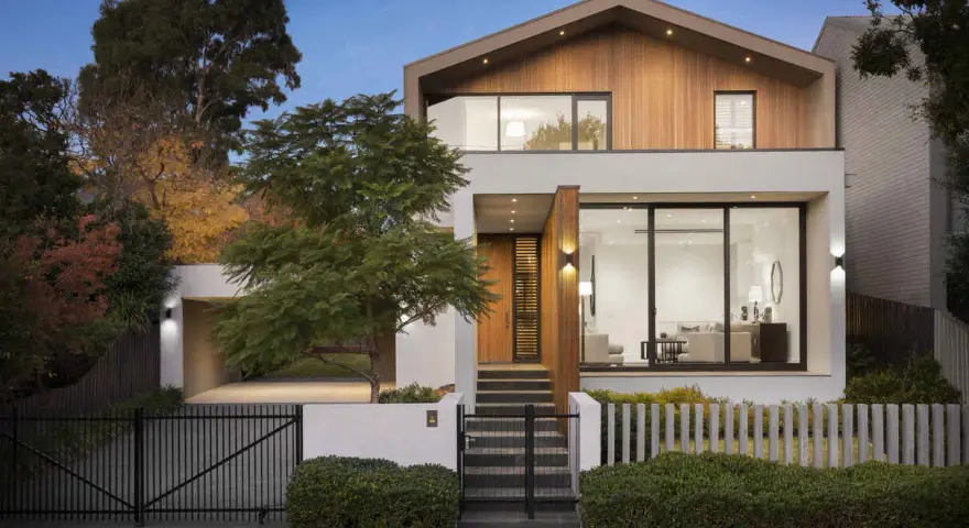 Moderna casa con **fachadas microcemento**, madera y grandes ventanales. Jardín cuidado y entrada acogedora.