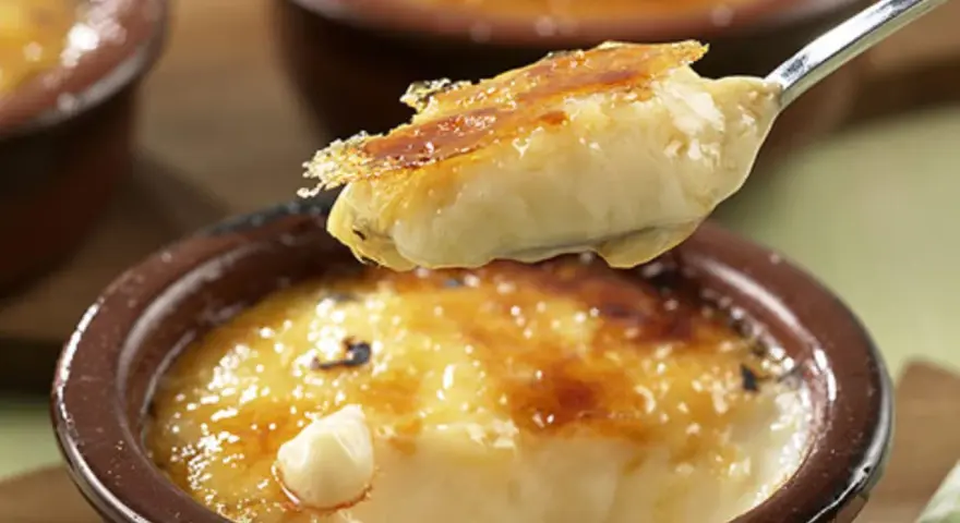 Cremige Crema Catalana Eis wird von einem Löffel aufgetischt, die karamellisierte Kruste bricht.