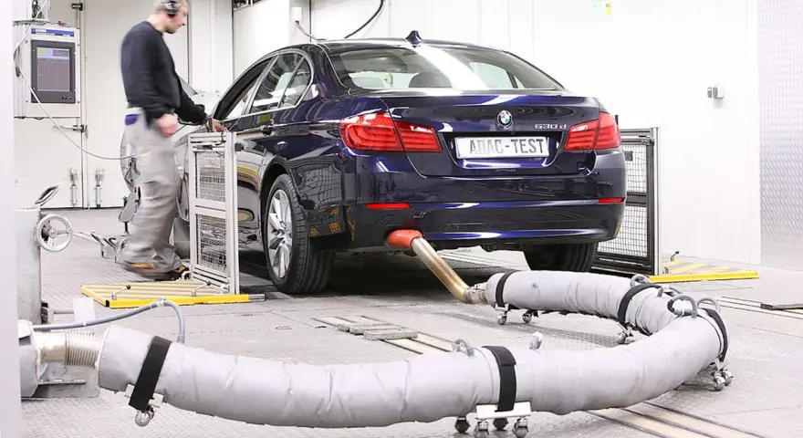 Blauer BMW auf einem Prüfstand für Abgastests. Ein Techniker überwacht die Messungen, die für die Euro 6-Abgasnorm relevant sind.