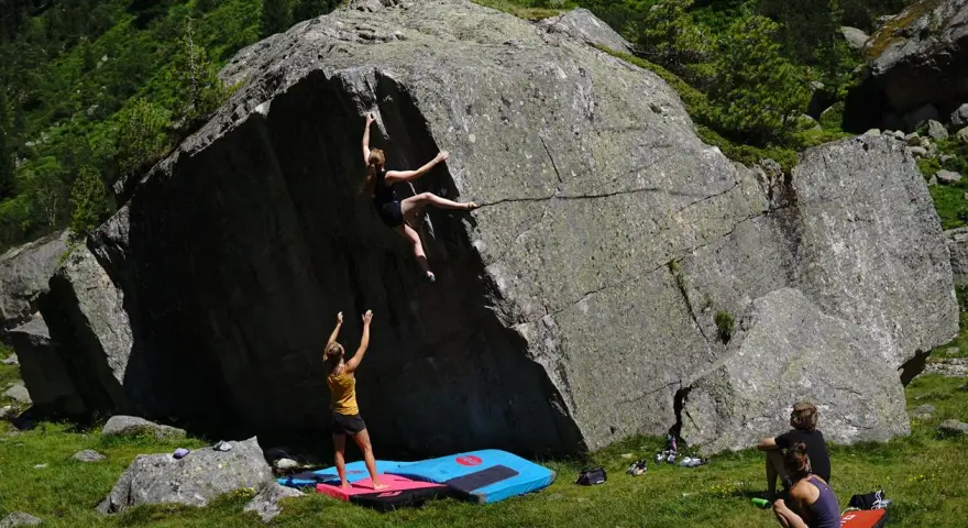 Zwei Frauen klettern an einem Felsen, eine oben, die andere unten. Das ist, was ist bouldern: Klettern ohne Seil an niedrigen Felsen.