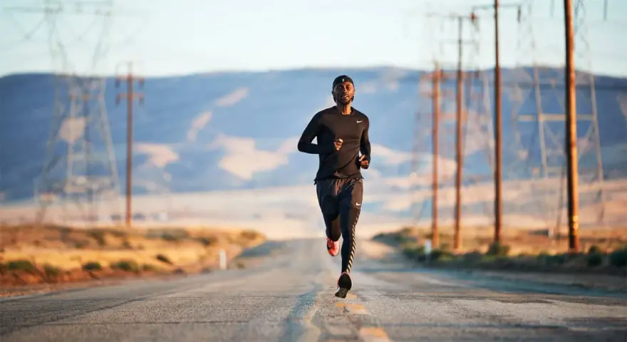 Un uomo corre su una strada deserta, circondato da tralicci dell'alta tensione. La corsa come fuga dalla depressione.