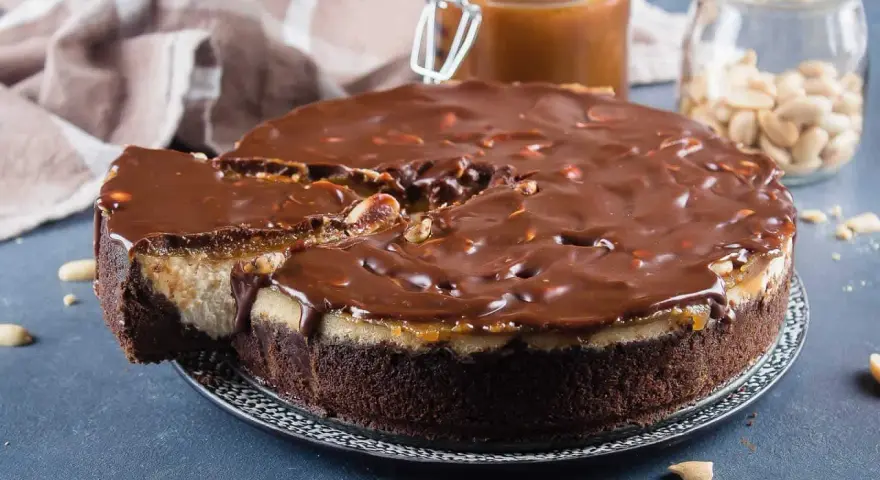 Gâteau façon Snickers, avec une base chocolatée, une couche crémeuse, du caramel coulant et une ganache au chocolat parsemée de cacahuètes. Un délice !